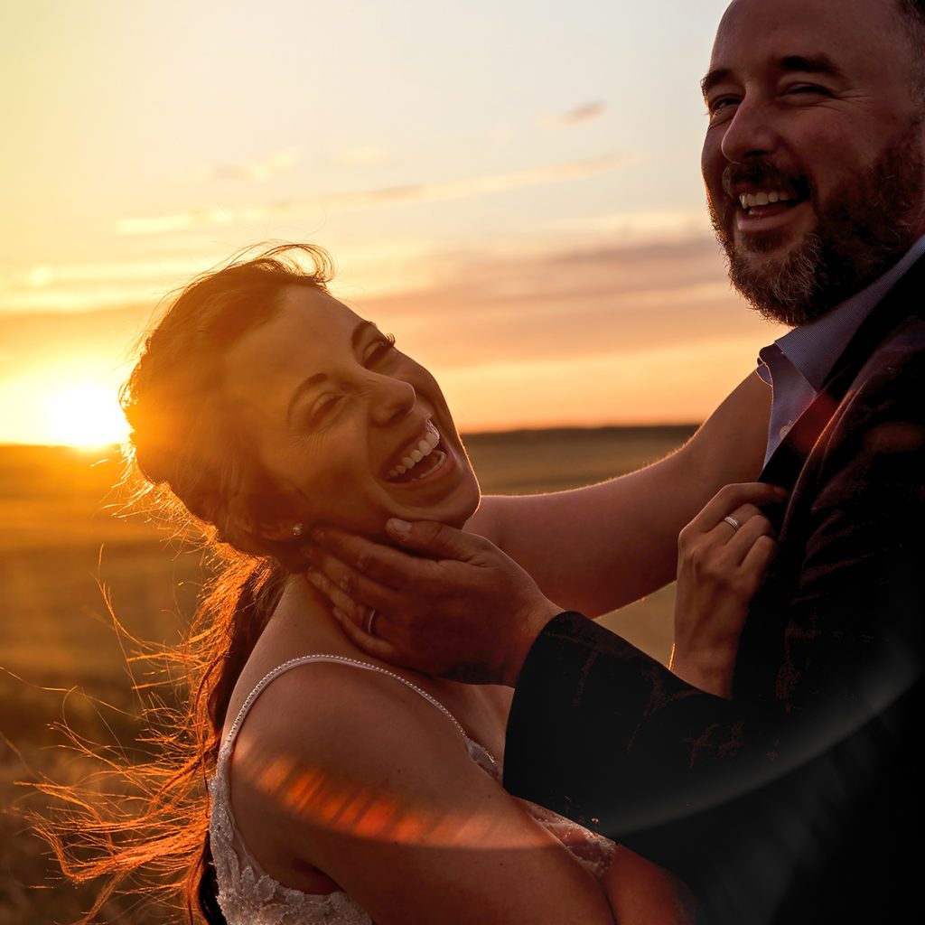 A Saskatchewan couple laughing together as the sun sets of their wedding day. Taken in Val Marie, Saskatchewan.